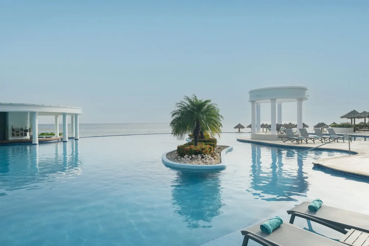 Infinity pool with loungers and ocean backdrop at Iberostar Selection Rose Hall Suites.