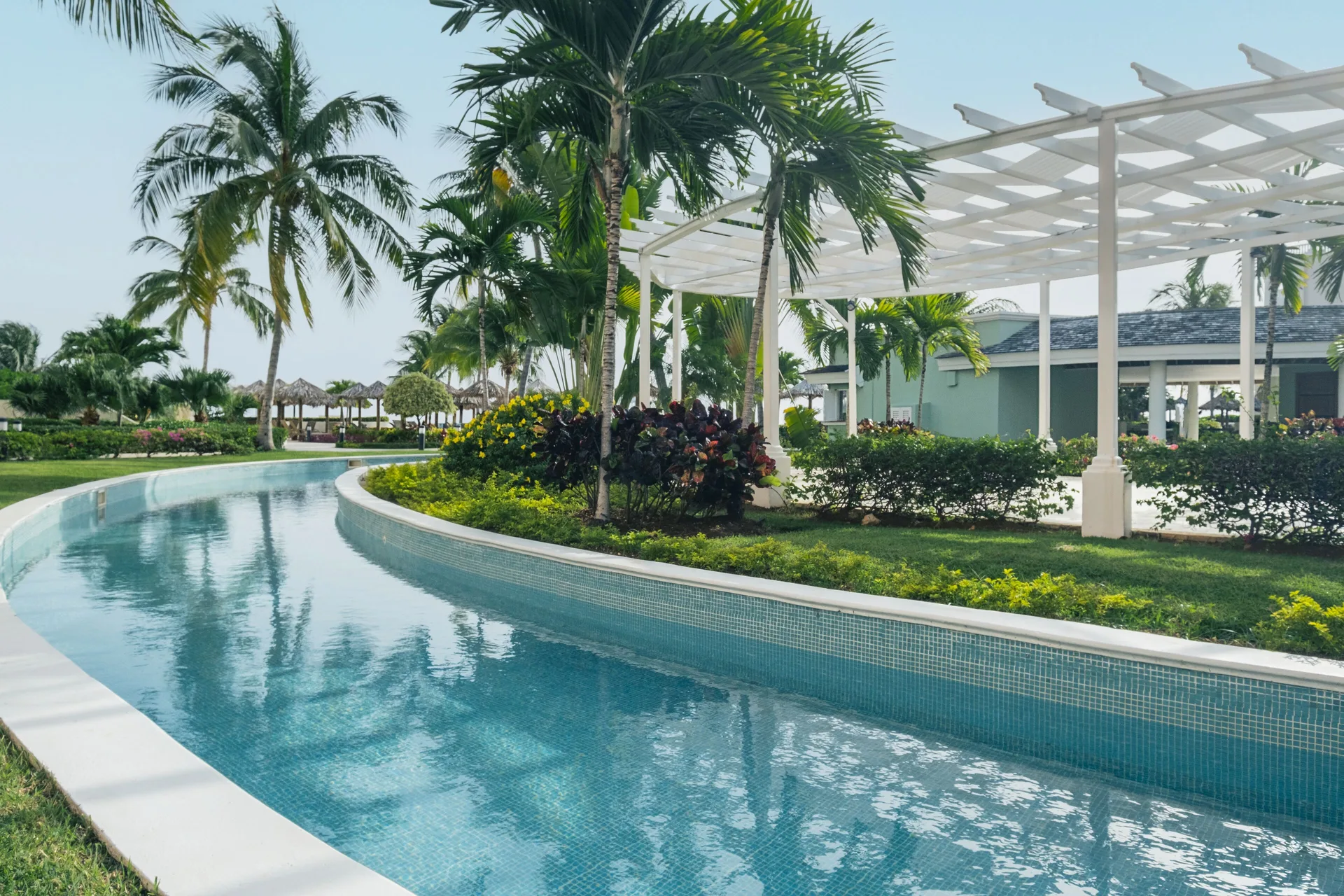 Lazy river pool with palms and pergola at Iberostar Selection Rose Hall Suites.