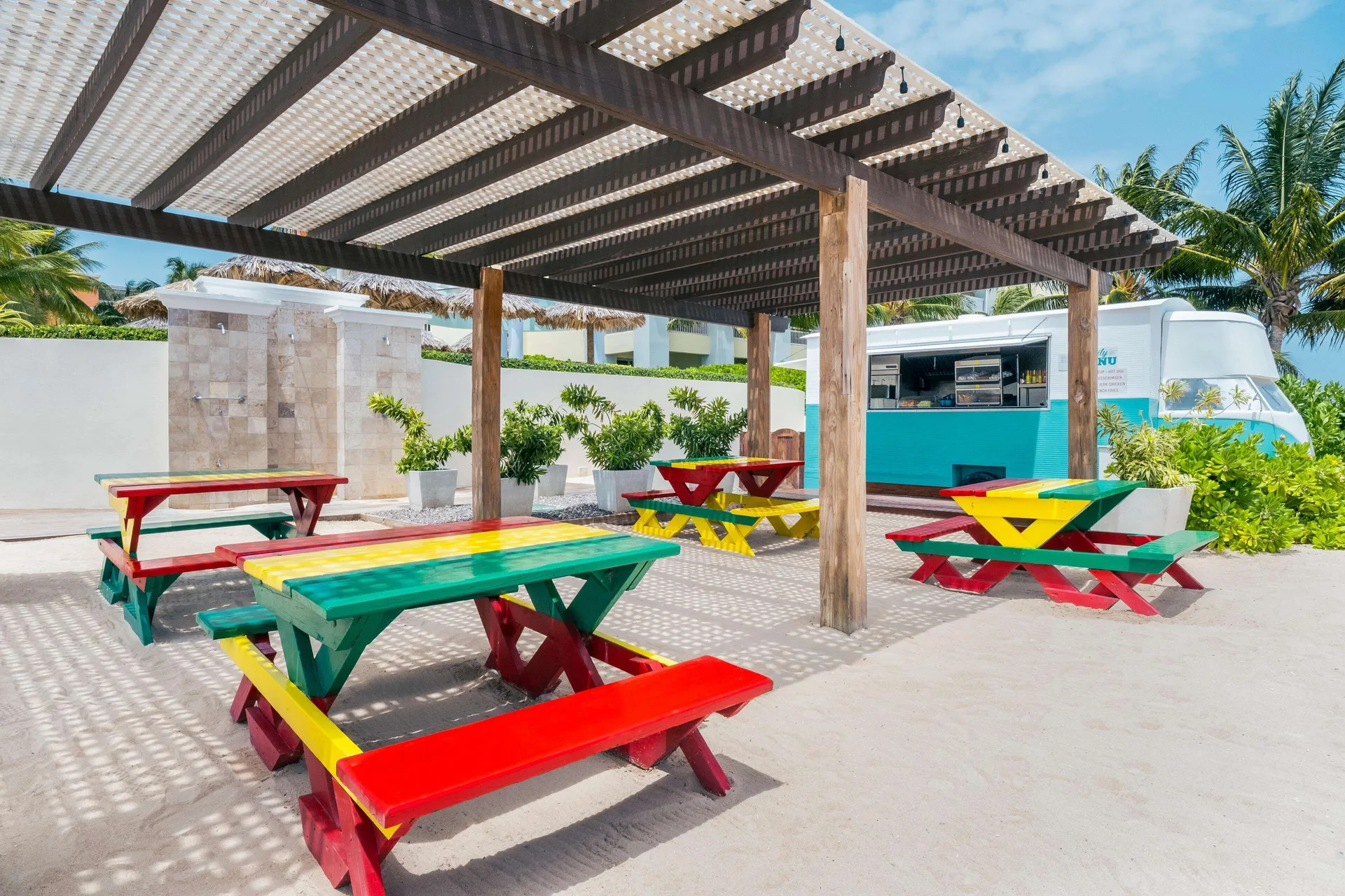 Colorful picnic tables by a food truck at Iberostar Selection Rose Hall Suites.