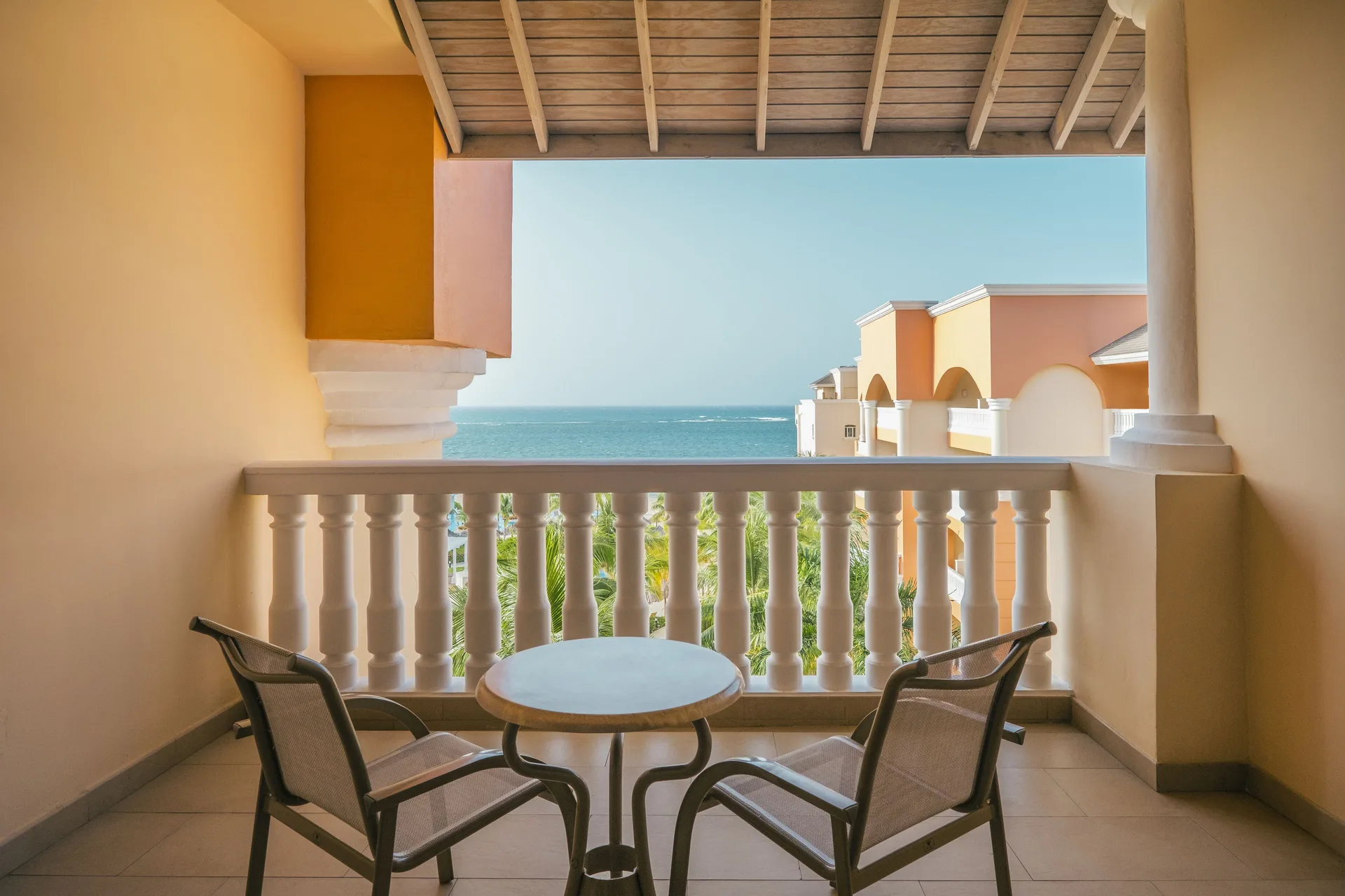 Junior Suite Ocean View balcony with chairs and sea view at Iberostar Selection Rose Hall Suites.