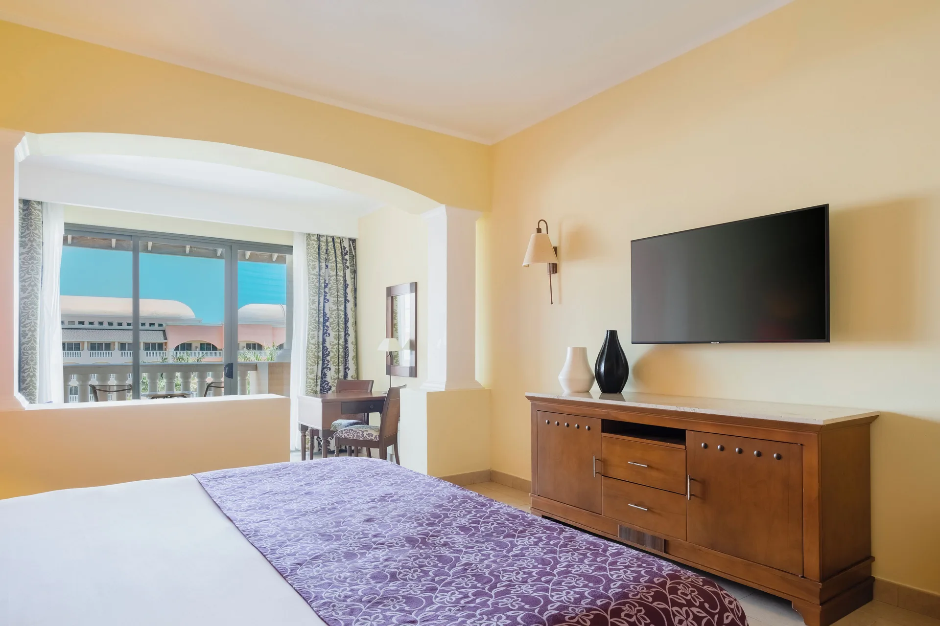 Junior Suite Ocean View bedroom with king bed and wall-mounted TV at Iberostar Selection Rose Hall Suites.