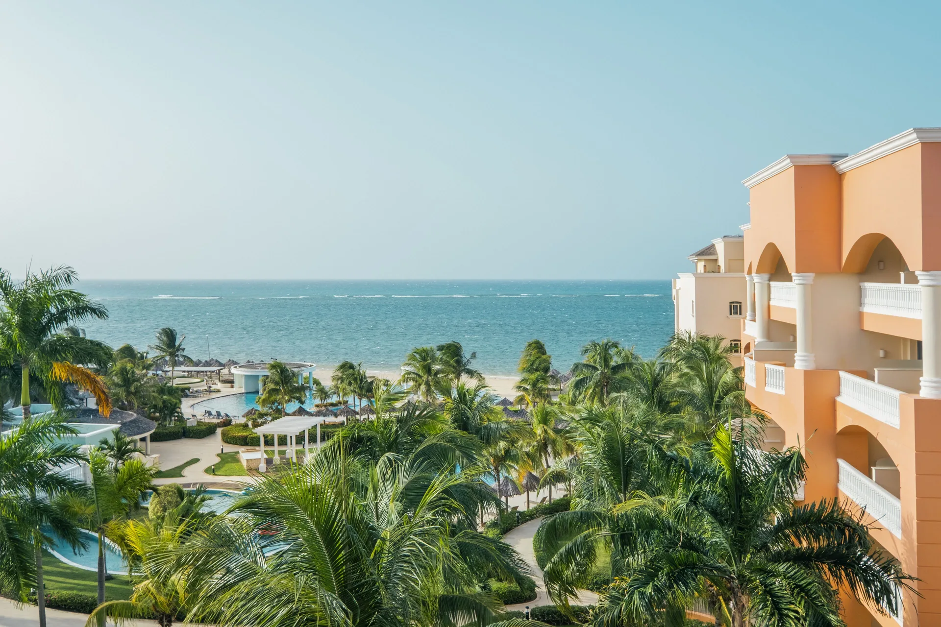 Junior Suite Ocean View outlook over palms, pools, beach, and sea at Iberostar Selection Rose Hall Suites.