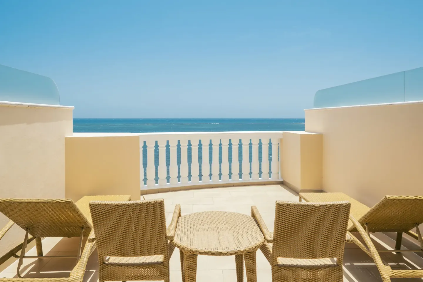 Oceanfront terrace with wicker seating at Iberostar Selection Rose Hall Suites.