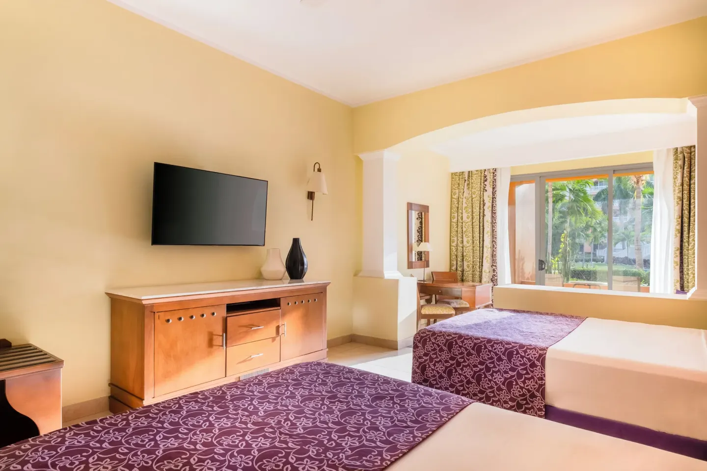 Junior Suite with two beds and a wall-mounted TV at Iberostar Selection Rose Hall Suites.