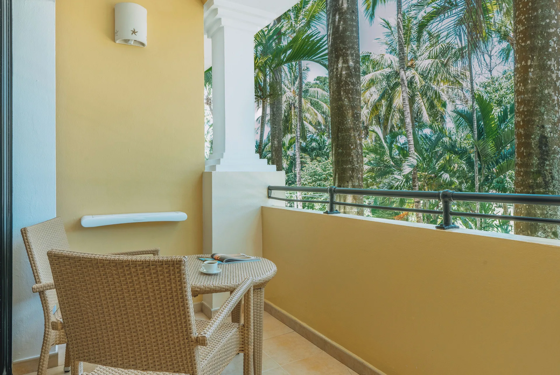 Balcony seating facing dense palms at Iberostar Waves Costa Dorada.