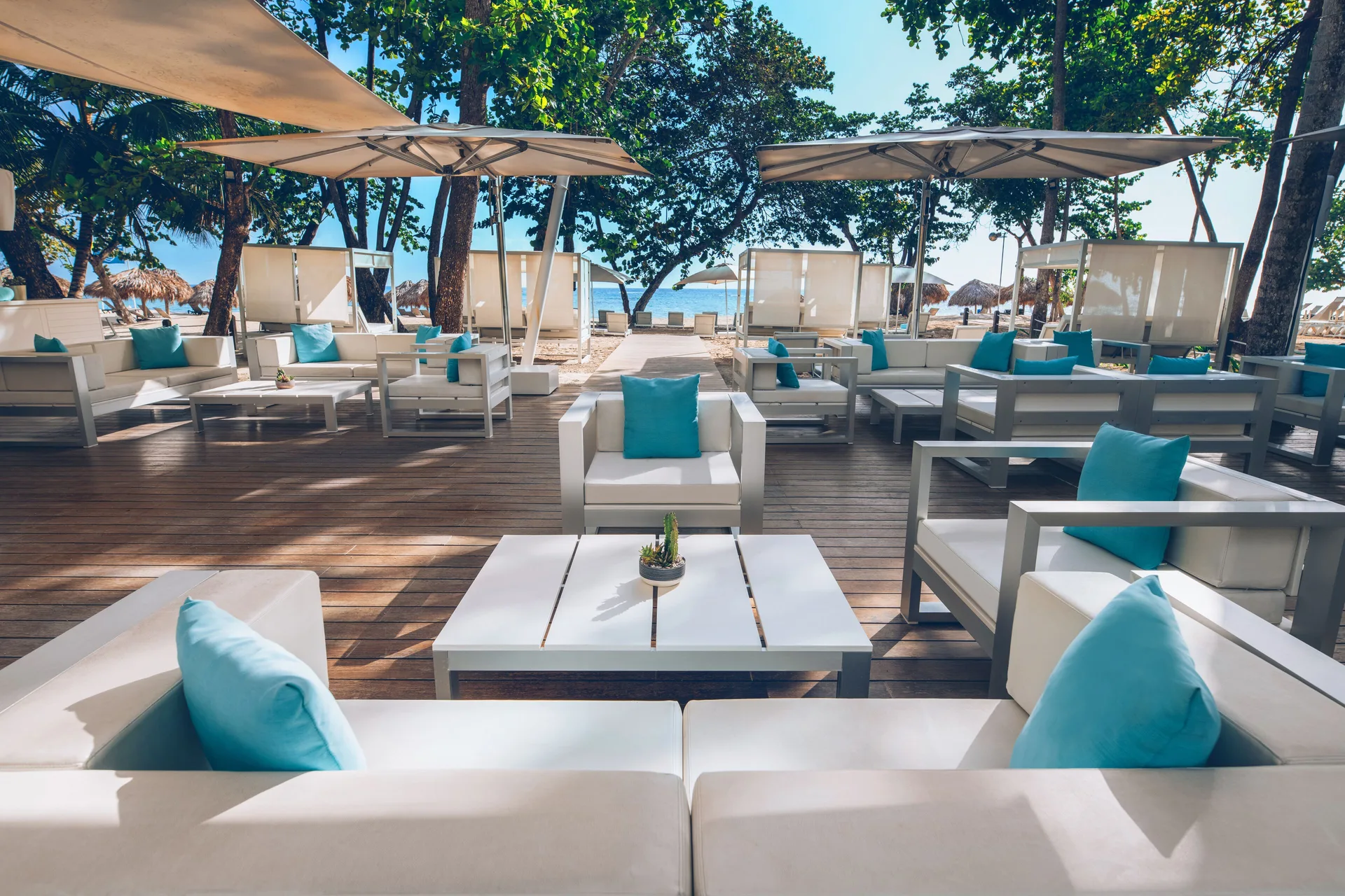 Beachfront lounge seating with turquoise pillows at Iberostar Waves Costa Dorada.