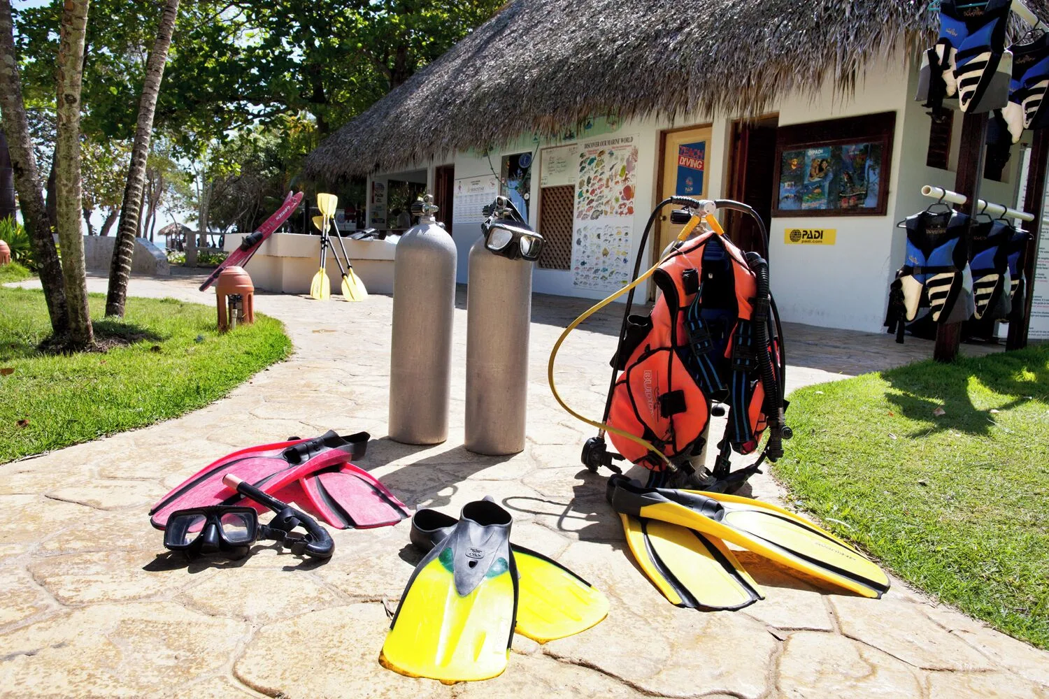 Scuba tanks, fins, masks, and dive gear near the beach at Iberostar Waves Costa Dorada.