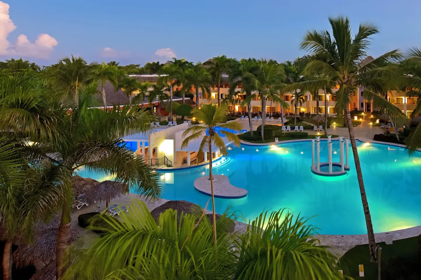 Illuminated resort pool at dusk at Iberostar Waves Costa Dorada.