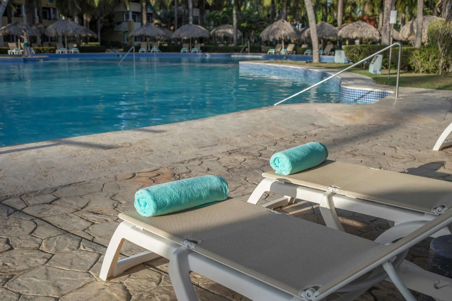 Pool loungers with rolled towels beside the water at Iberostar Waves Costa Dorada.