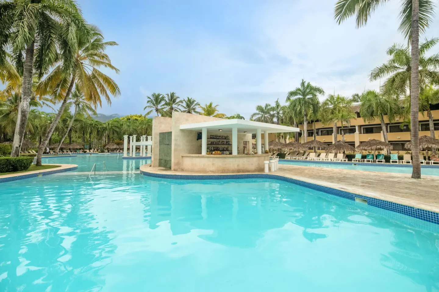 Swim-up pool bar surrounded by palm trees at Iberostar Waves Costa Dorada.