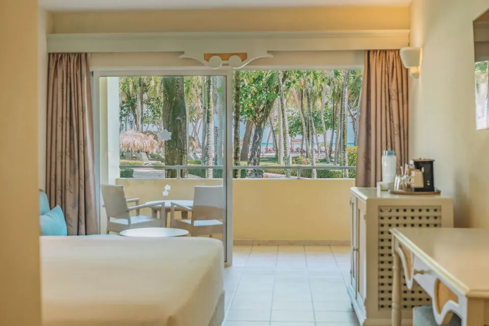Premium Room Ocean View with bed, balcony, and palm-framed sea view at Iberostar Waves Costa Dorada.