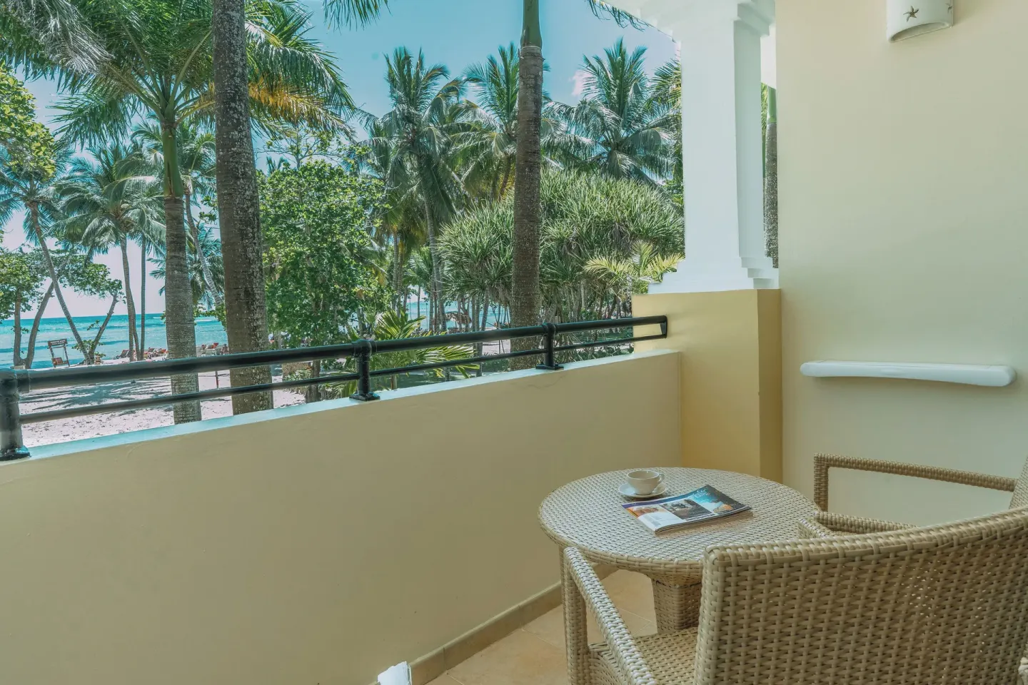 Oceanfront Premium Room balcony with wicker seating and palm-framed sea view at Iberostar Waves Costa Dorada.