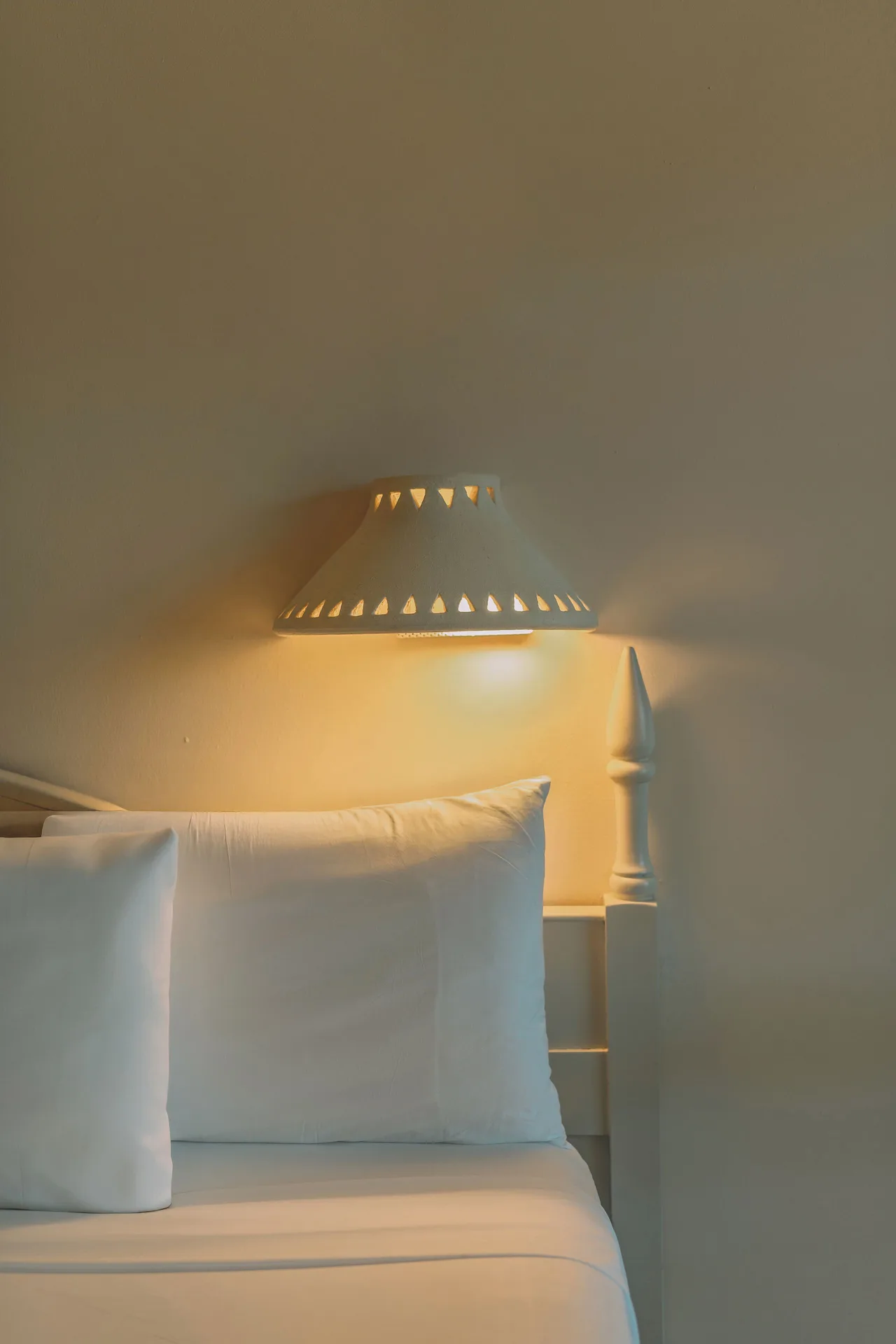 Premium Tropical View Room bed detail with pillow and wall lamp at Iberostar Waves Costa Dorada.