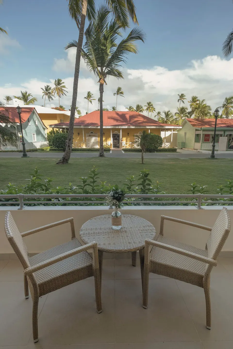 Balcony seating with two chairs and a table overlooking palms at Iberostar Waves Dominicana.