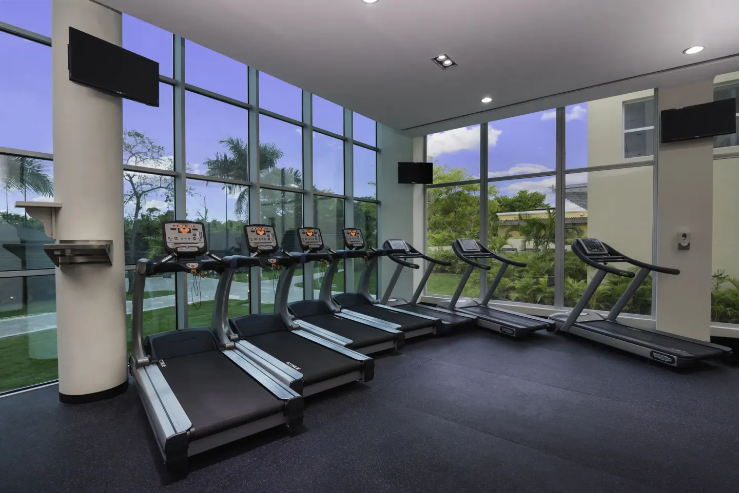 Treadmills line floor-to-ceiling windows in the fitness center at Iberostar Waves Dominicana.
