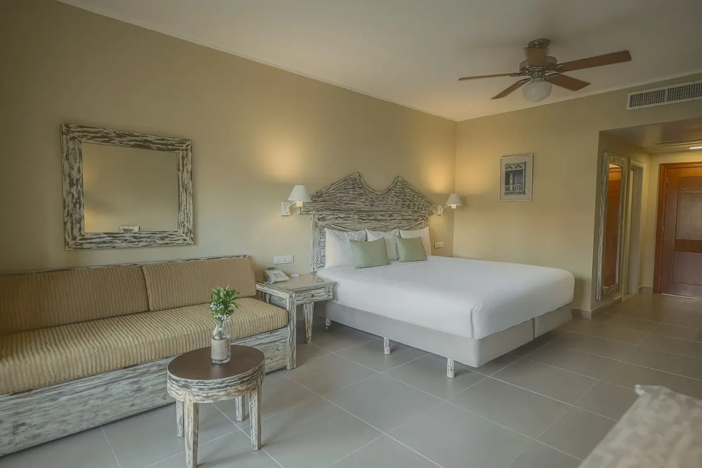 Guest room with king bed, sofa and small round table at Iberostar Waves Dominicana.
