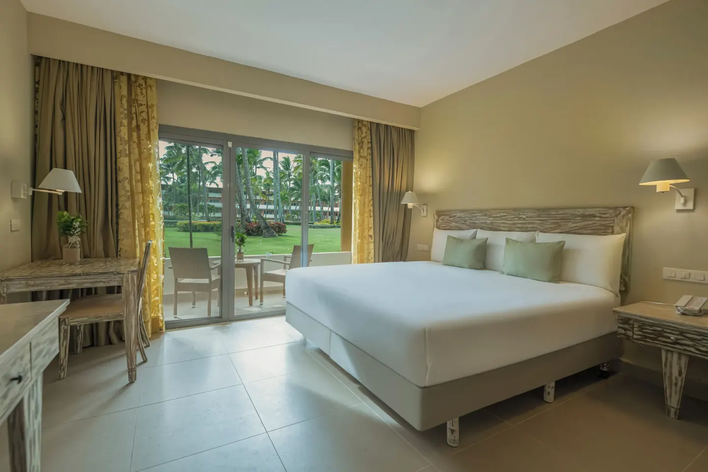 King guest room with garden-facing patio doors and writing desk at Iberostar Waves Dominicana.