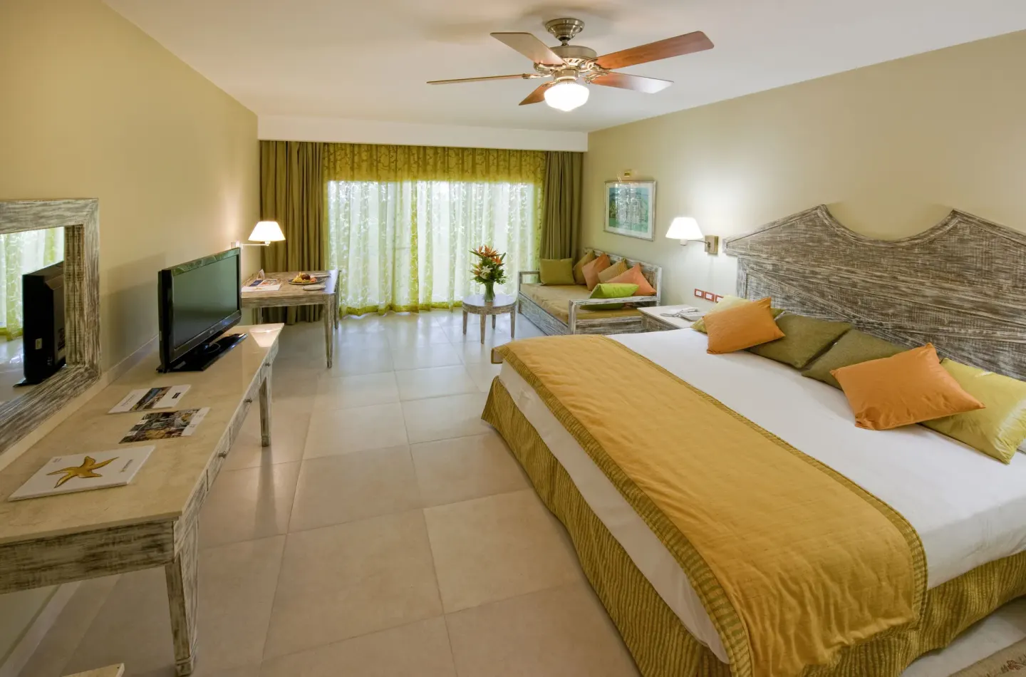 King guest room with sofa, TV, desk and balcony doors at Iberostar Waves Dominicana.