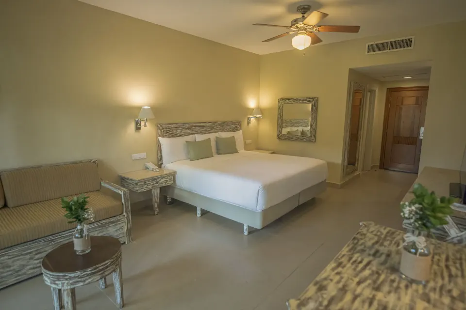 King guest room with sofa seating, bedside lamps and entry hallway at Iberostar Waves Dominicana.