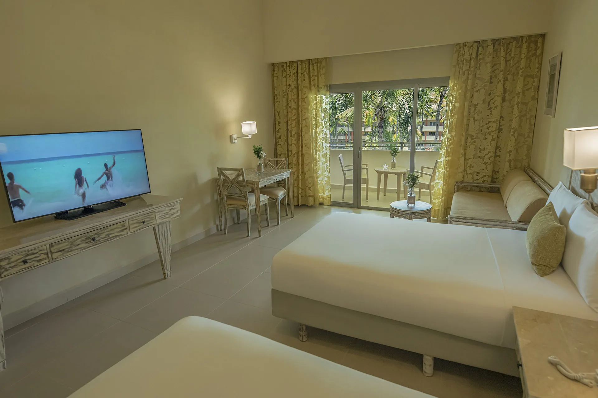 Guest room with two beds, TV and balcony doors at Iberostar Waves Dominicana.