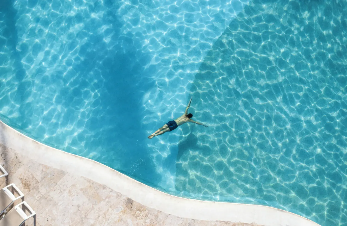 Overhead view of a swimmer floating in a blue pool at Iberostar Waves Dominicana.