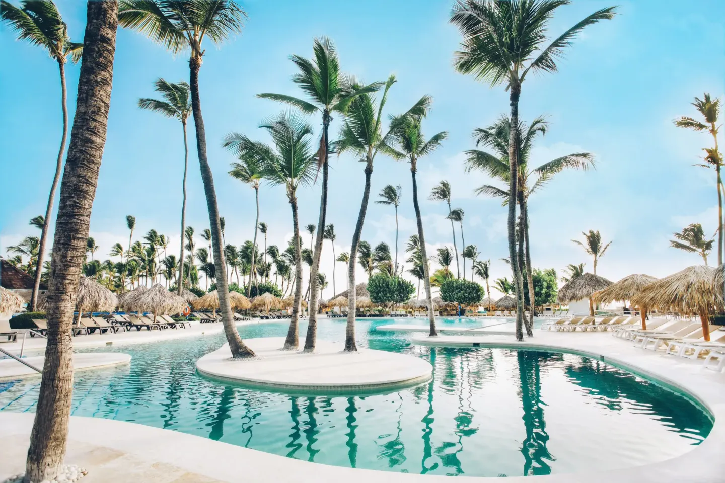 Curving palm-lined pool with lounge chairs at Iberostar Waves Dominicana.