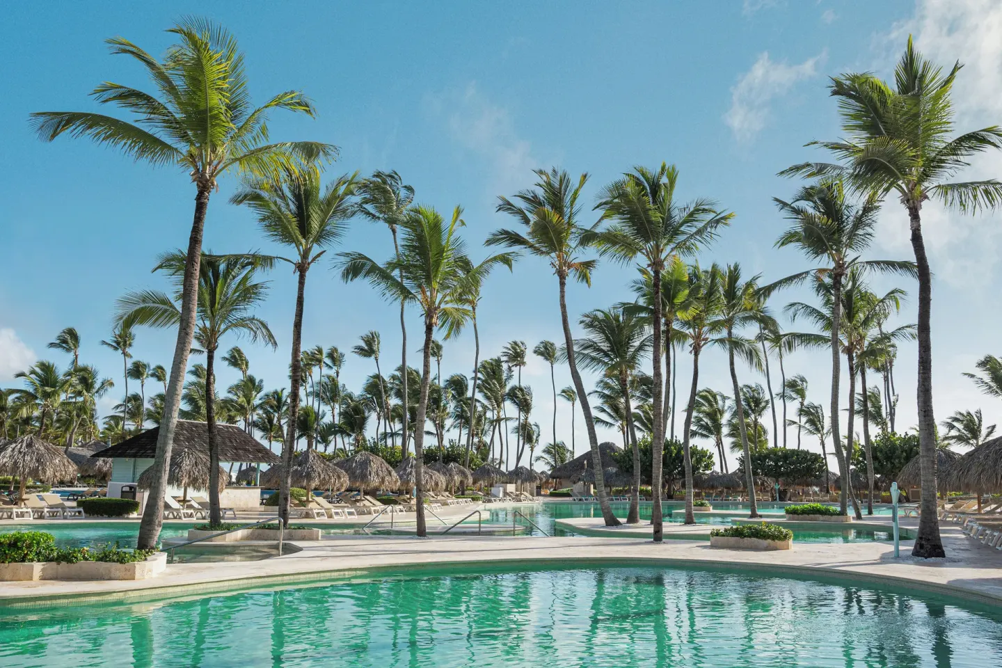 Palm-lined pool deck with railings, loungers, and palapas at Iberostar Waves Dominicana.