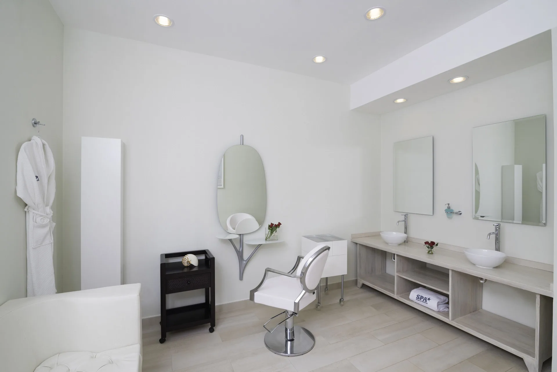 Spa salon room with styling chair, mirrors, sinks and robe at Iberostar Waves Dominicana.