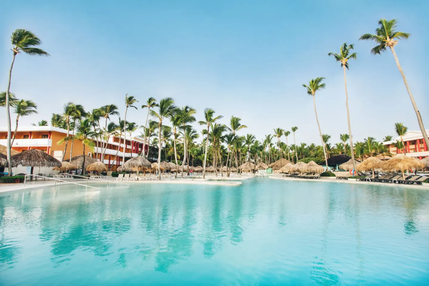 Wide pool with palms, palapas, loungers, and resort buildings at Iberostar Waves Dominicana.