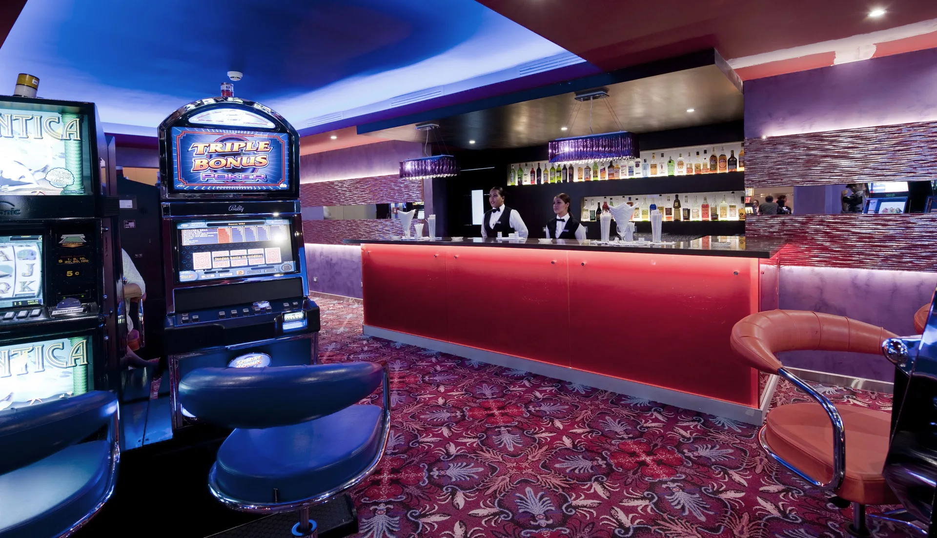 Casino bar with slot machines and red counter at Iberostar Waves Dominicana.
