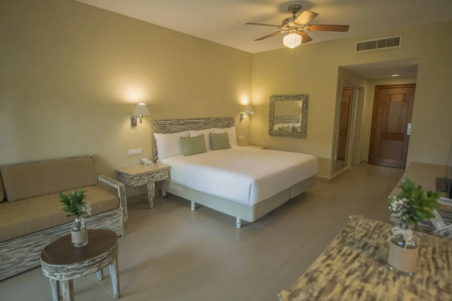 Premium Room Tropical View king bed with sofa and entry area at Iberostar Waves Dominicana.