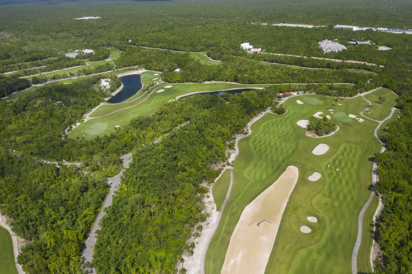 Aerial view of a golf course with water features near Iberostar Waves Paraíso Beach.