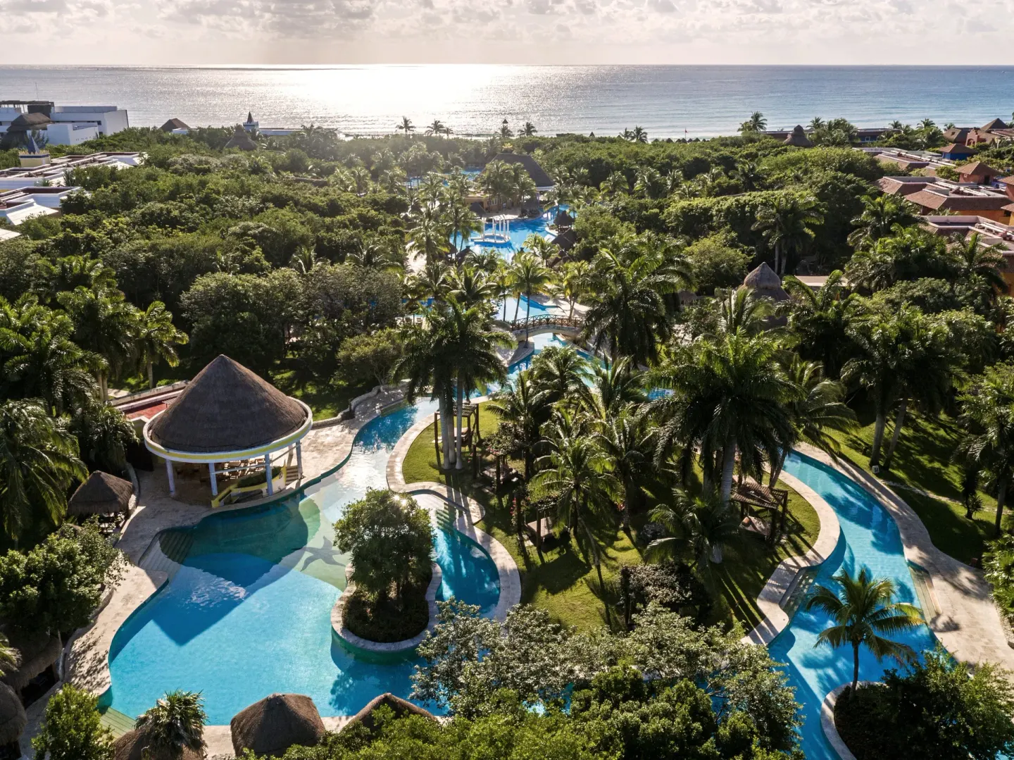 Aerial view of pools, palms, and the ocean at Iberostar Waves Paraíso Beach.