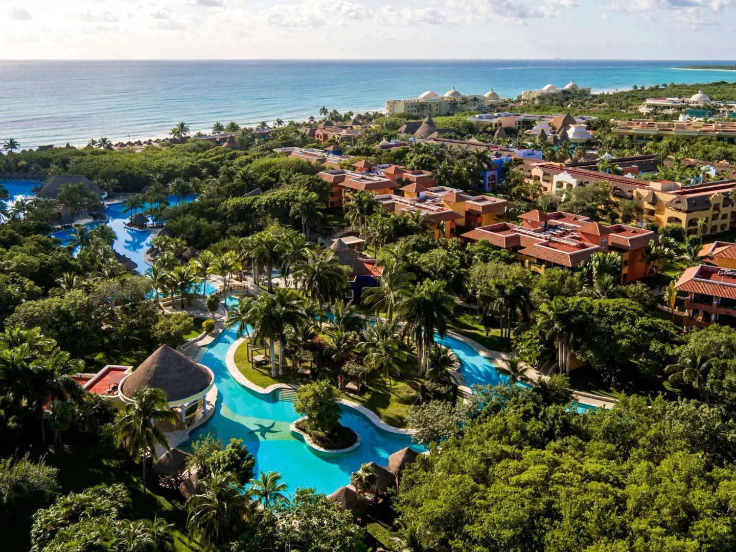 Aerial view of resort buildings, pools, palms, and coastline at Iberostar Waves Paraíso Beach.