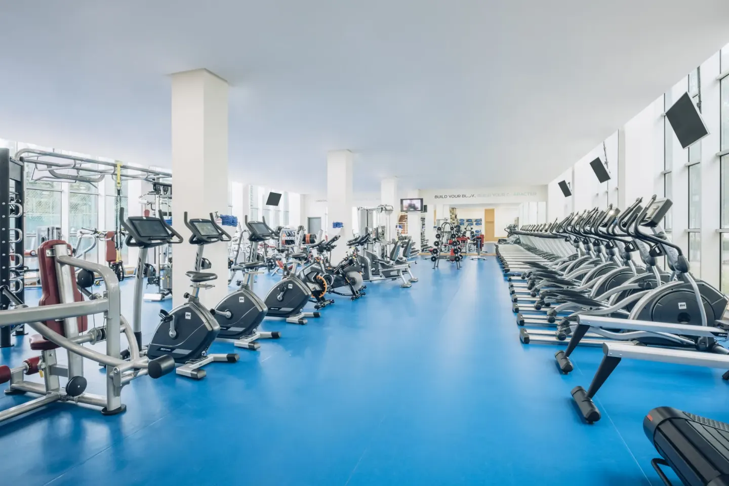 Bright fitness center with cardio and weight machines at Iberostar Waves Paraíso Beach.