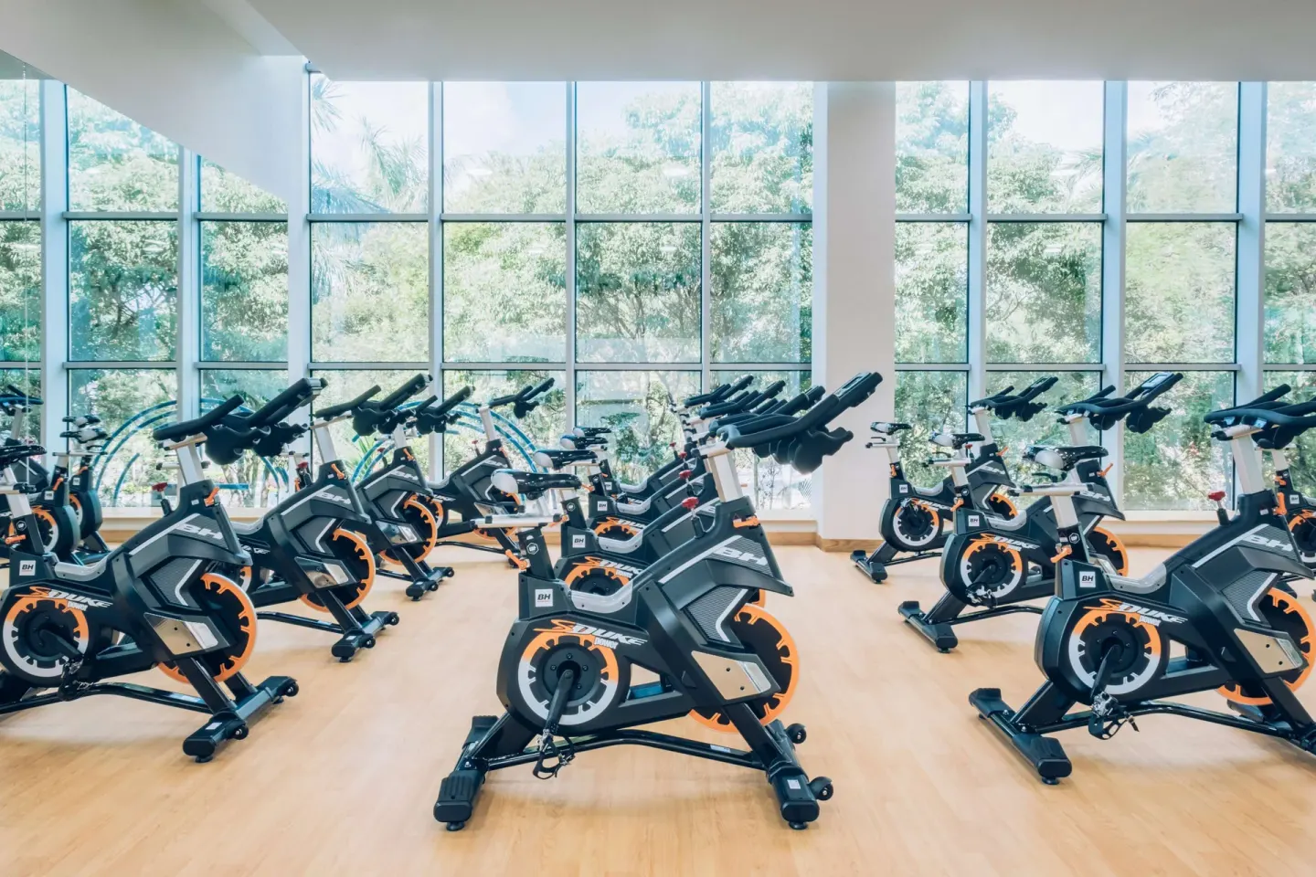 Rows of indoor cycling bikes in a windowed studio at Iberostar Waves Paraíso Beach.