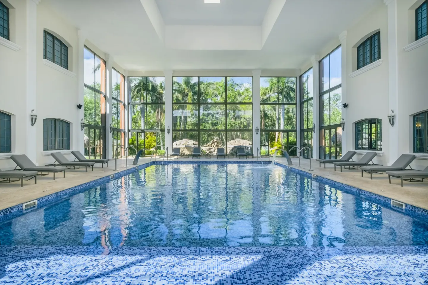 Indoor pool with lounge chairs and palm views at Iberostar Waves Paraíso Beach.
