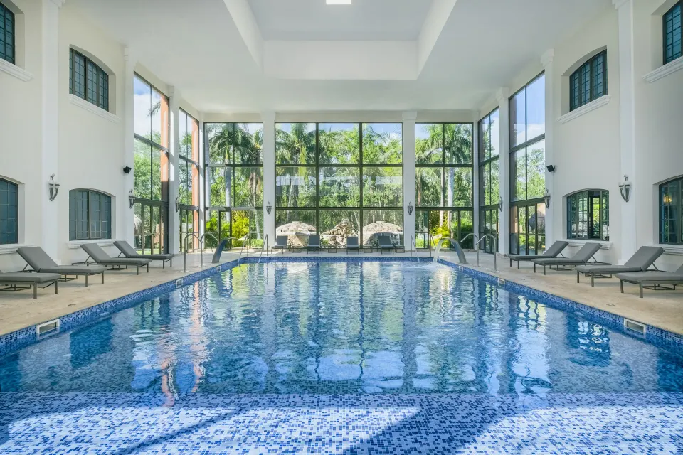 Indoor pool with lounge chairs and palm views at Iberostar Waves Paraíso Beach.