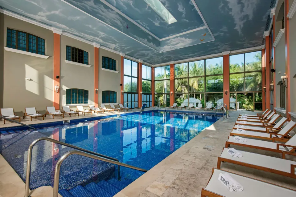 Indoor pool with loungers and a sky-painted ceiling at Iberostar Waves Paraíso Beach.