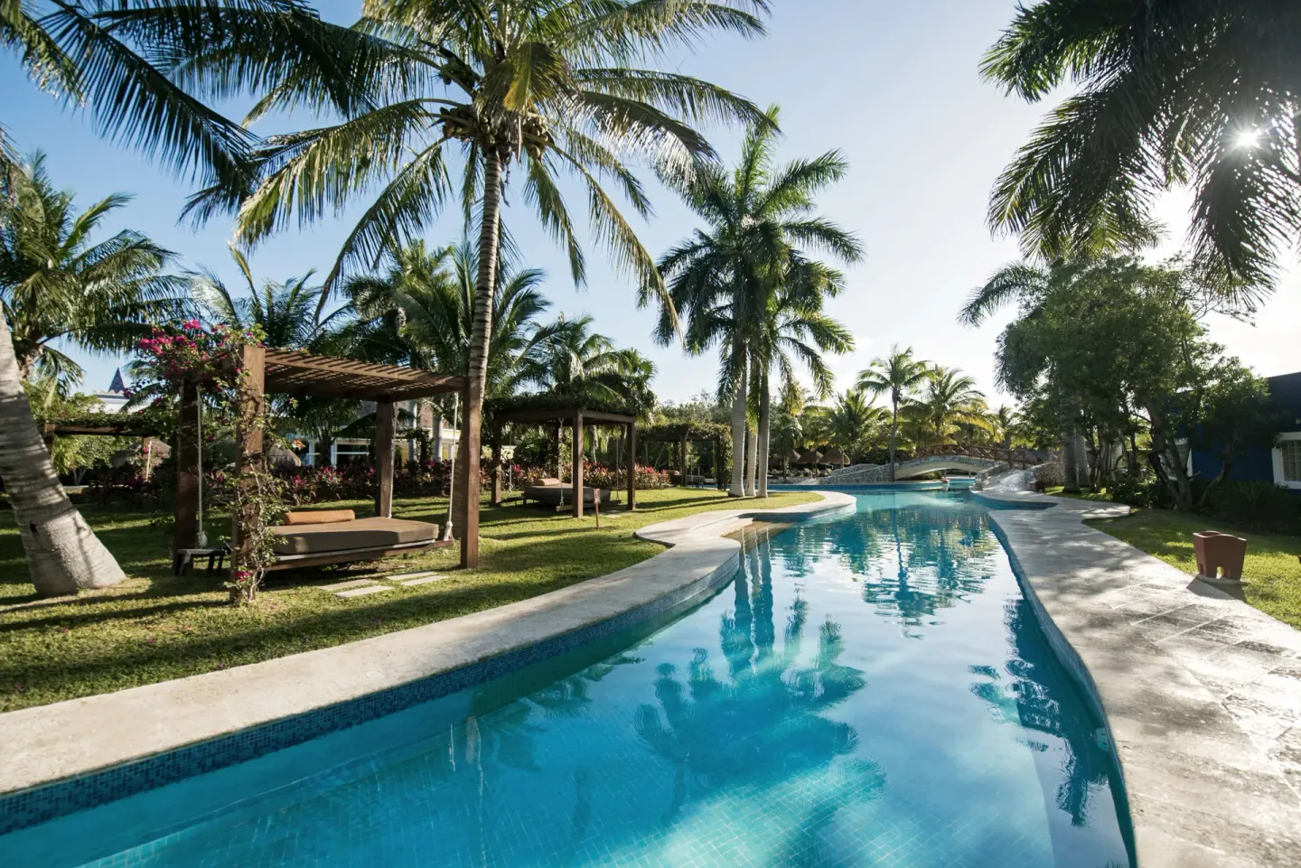 Quiet pool channel with palm trees and cabanas at Iberostar Waves Paraíso Beach.
