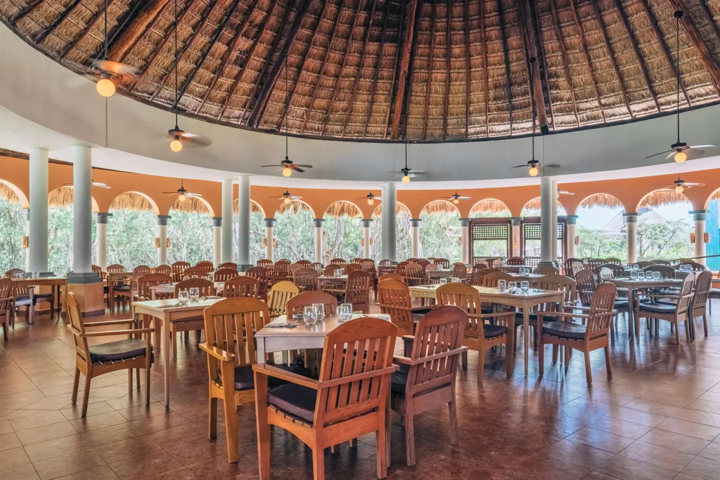 Large palapa-roof dining room with set wooden tables at Iberostar Waves Paraíso Beach.