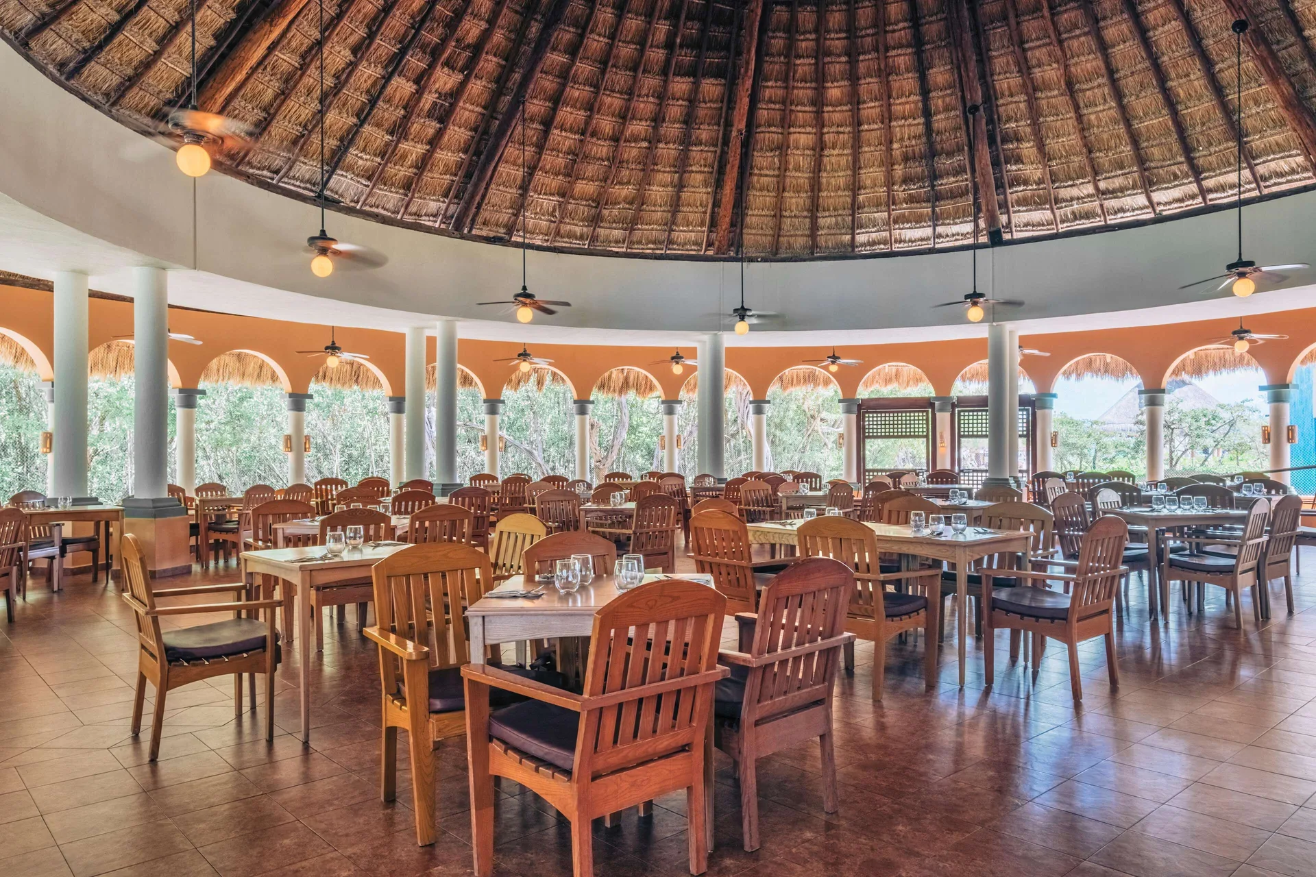 Large palapa-roof dining room with set wooden tables at Iberostar Waves Paraíso Beach.