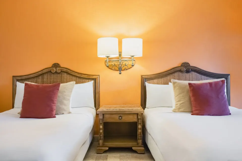 Two double beds in a Junior Suite at Iberostar Waves Paraíso Beach with warm orange wall lighting.