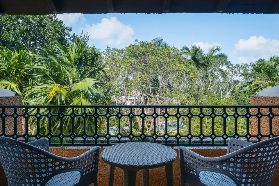Premium Room Poolside balcony with chairs and tropical greenery at Iberostar Waves Paraíso Beach.