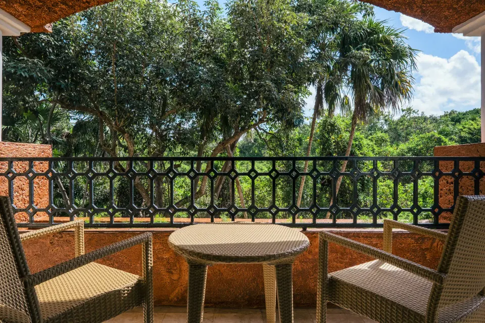Premium Room balcony with wicker chairs and tropical trees at Iberostar Waves Paraíso Beach.