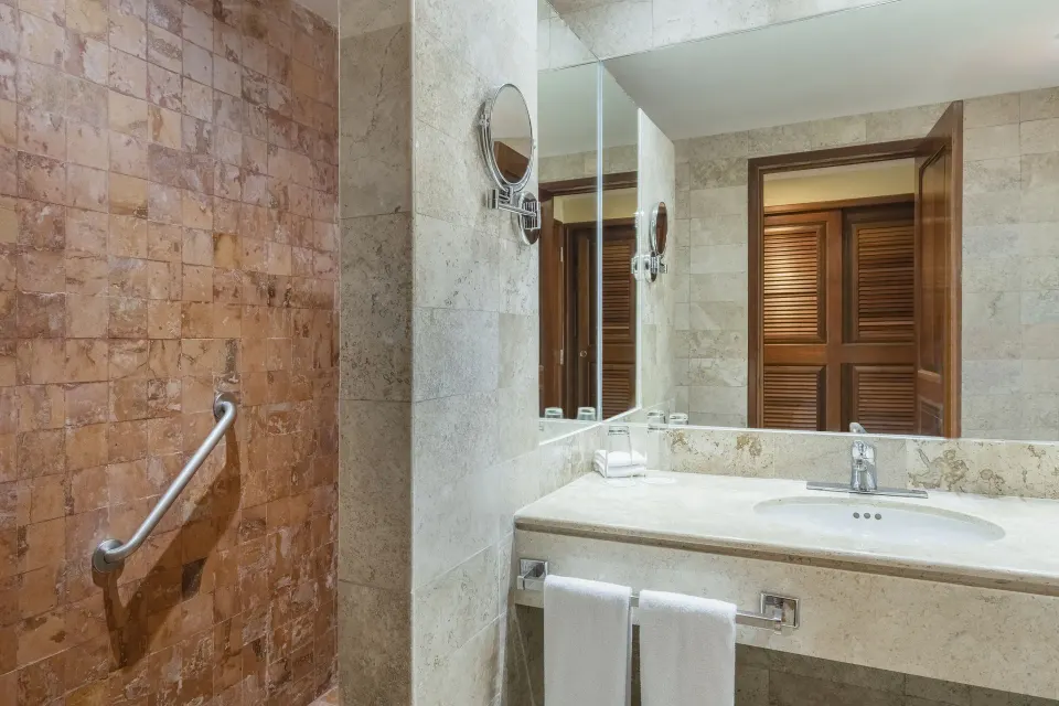 Premium Room bathroom with vanity, mirror, and tiled shower at Iberostar Waves Paraíso Beach.