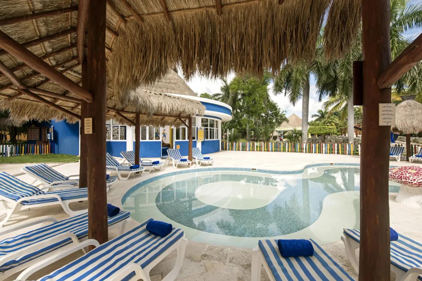 Children’s pool with striped loungers and thatched shade at Iberostar Waves Paraíso del Mar.