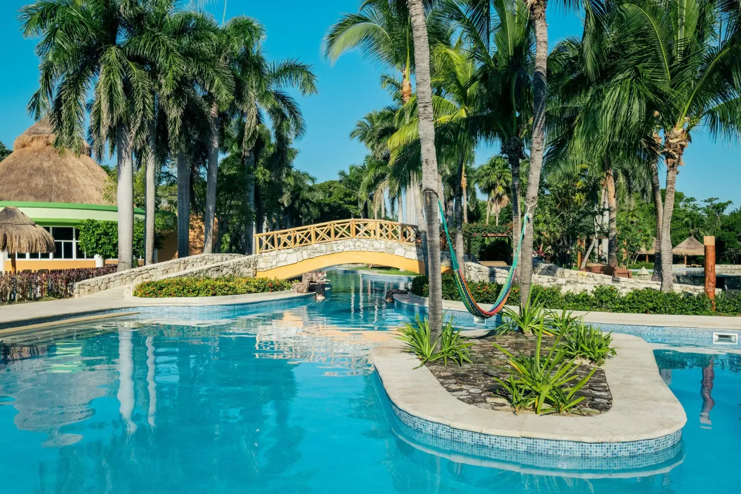 Pool island with palms and a bridge at Iberostar Waves Paraíso del Mar.