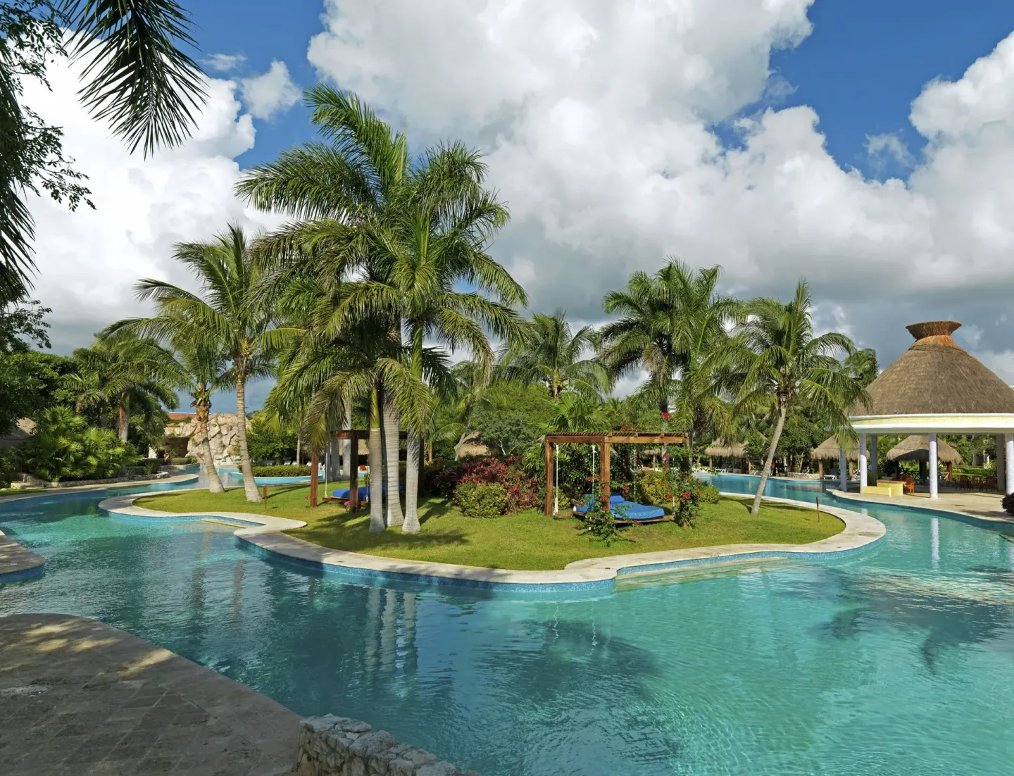 Pool gardens with palms, loungers, and a pavilion at Iberostar Waves Paraíso del Mar.