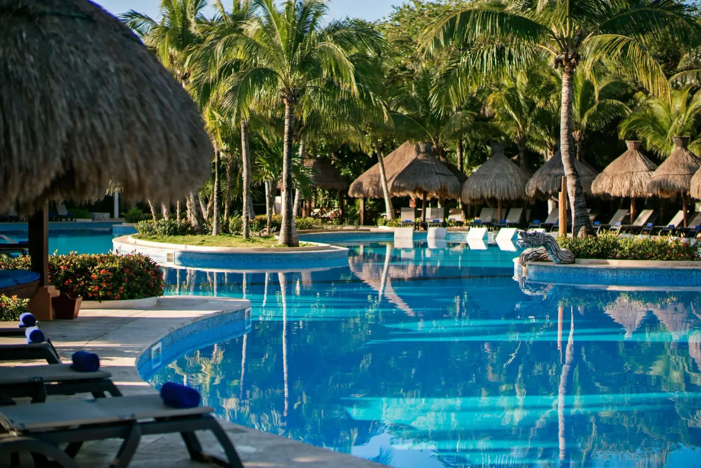 Pool with loungers, palapas, and tropical palms at Iberostar Waves Paraíso del Mar.